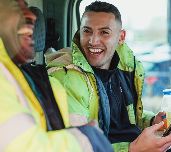 Two men in high-vis jackets laughing in a van